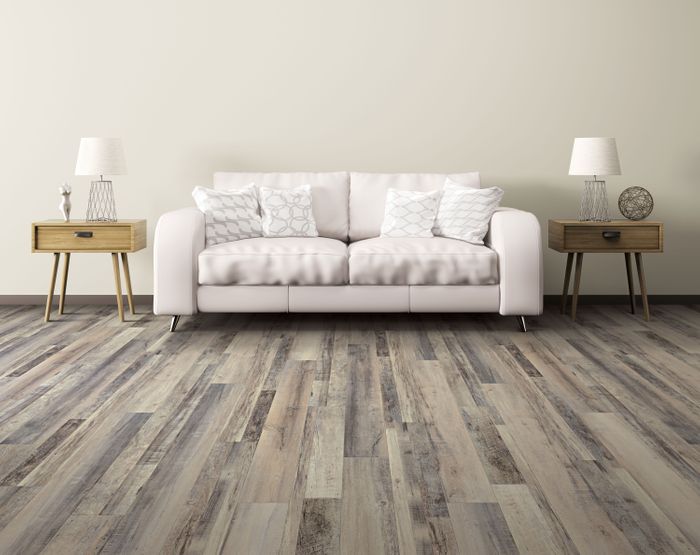 A white couch in a living room with distressed wooden flooring.